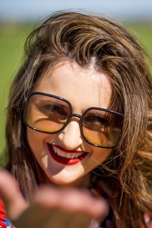 Cheerful woman in sunglasses looking at camera on sunny day