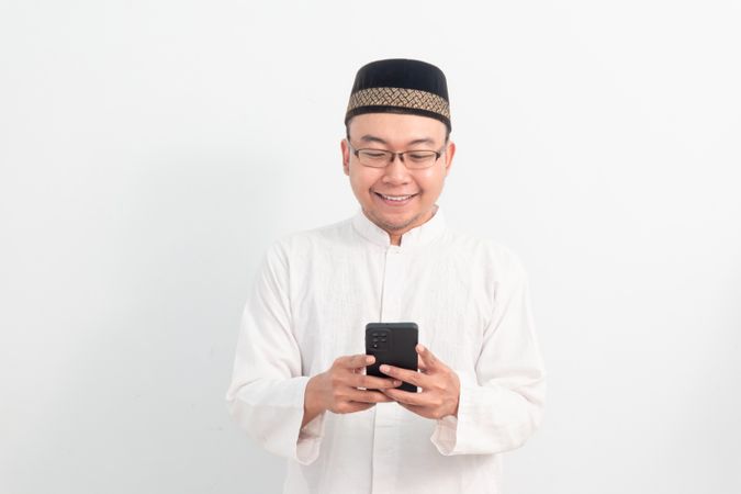 Asian Muslim man smiling holding phone pose, Ramadan