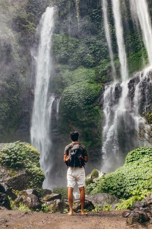 Full length shot of young male hiker looking at waterfall