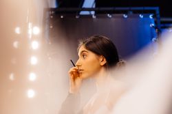 brunette female in peignoir applying makeup