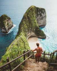 Man on viewpoint above tropical seashore with cliffs