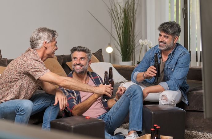 Cheerful men drinking beer and joking at home