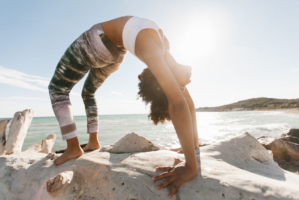 Sportive woman performing yoga posture on stones in nature