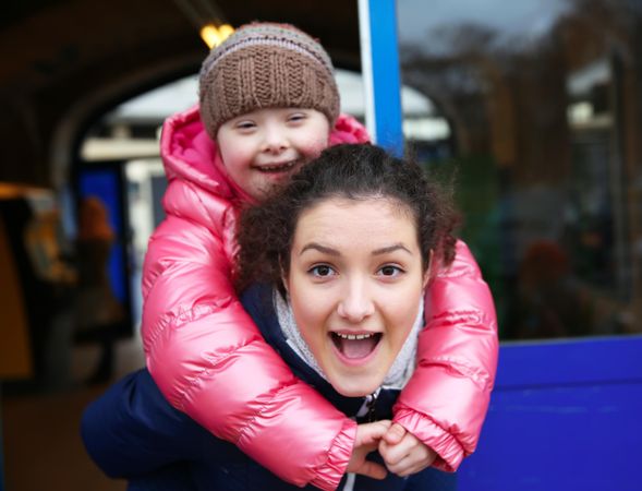 A young girl with Down syndrome playing with her teenager sister