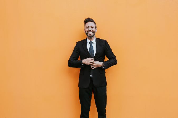 Adult stylish man in costume near orange wall