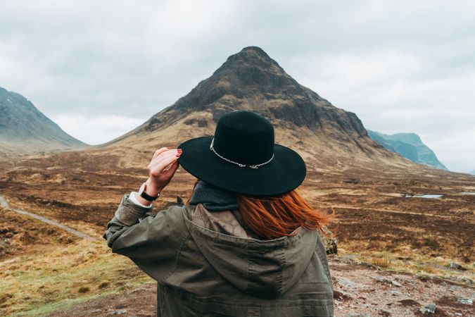 Redhead woman in hat against mountains