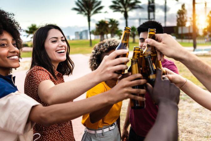 Multi-ethnic friends toasting with beer at sunset
