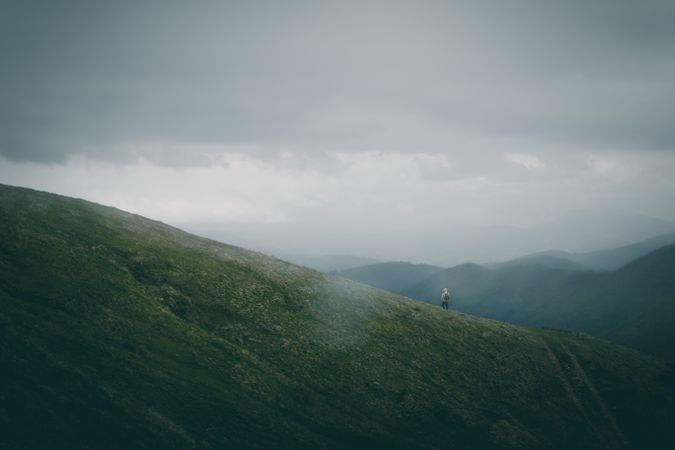 Anonymous traveler walking on path on hillside