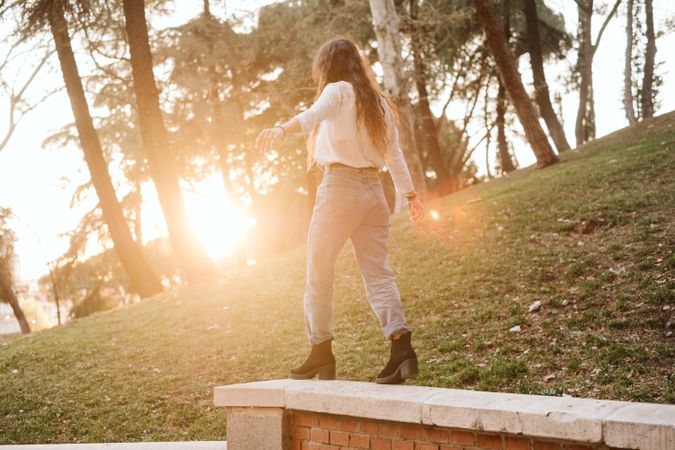 Anonymous young woman walking on border in park