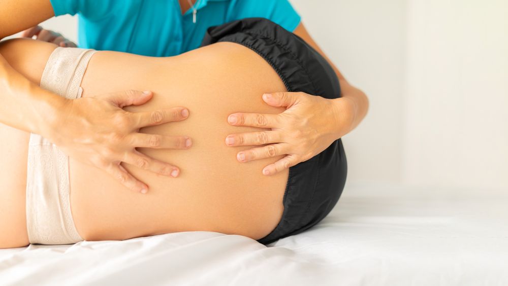 A female physical therapist performs a stretching and pressure exercise on her patient's lower back