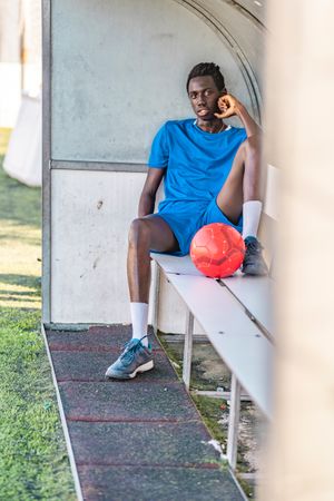 Black football player resting on bench