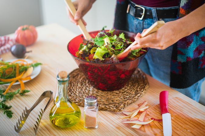 Crop woman preparing vegetable salad