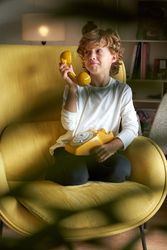 Content boy with retro yellow telephone in room