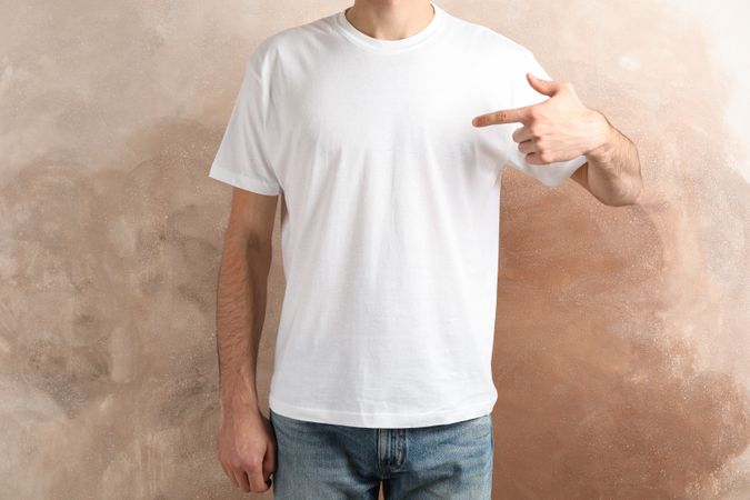 Men in blank t-shirt against brown background, space for text