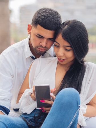 Man bonging smiling woman having fun with smartphone
