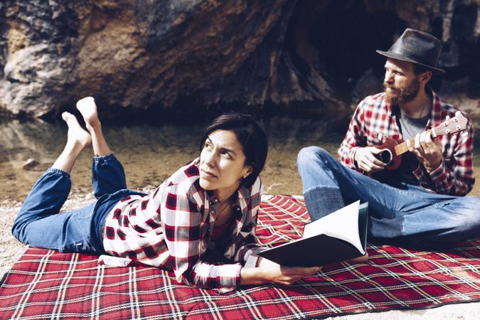 Chilling couple with book and guitar on shore