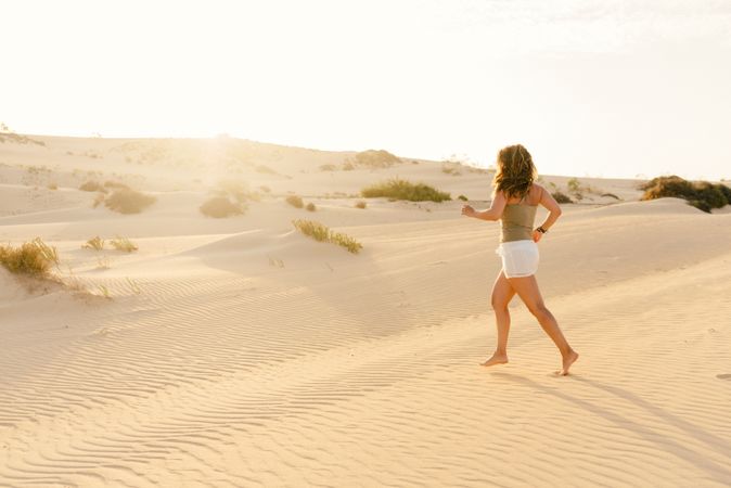 Active woman running in dry desert barefoot