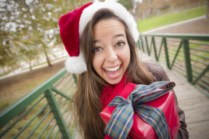 Excited Woman Wearing a Santa Hat with Wrapped Gift