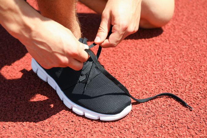 Man tying shoelaces on red athletic running track, close up