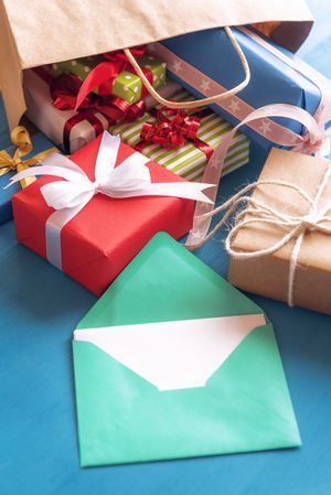 Open envelope and colorful gifts on blue table