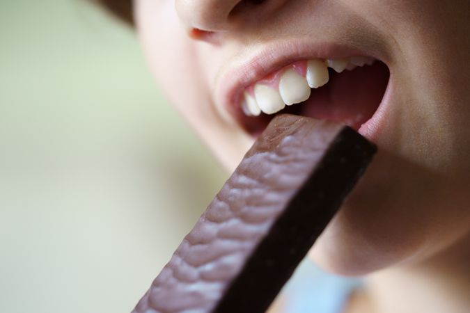 Anonymous teenage girl taking a bite of protein bar