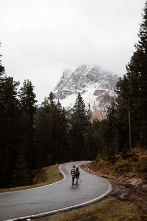Casual resting couple standing in an embrace on route amid forest