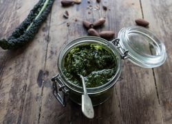 Jar with kale pesto near nuts