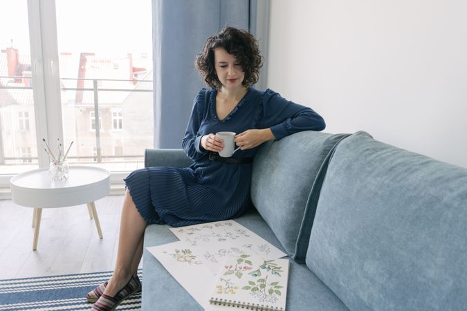 Young brunette woman with coffee looking album with pictures