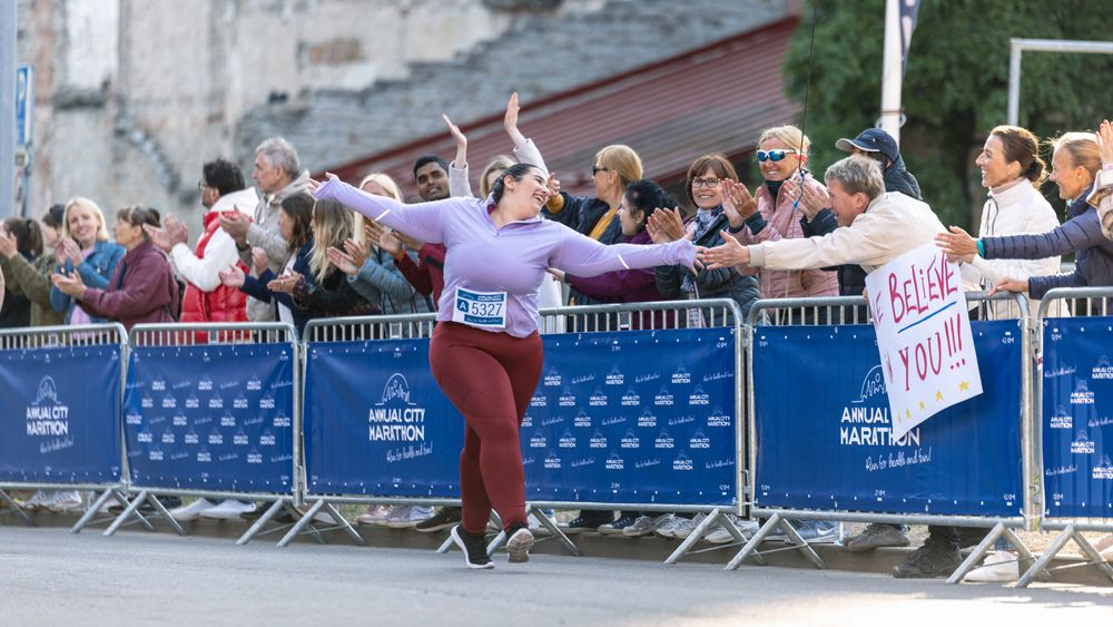 Portrait of a Smiling Plus Size Female Runner Crossing the Finish Line and Demonstrating her Willpower.