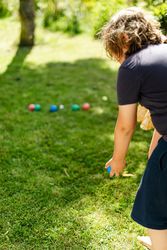 Back view of a person throwing a blue ball standing on green grass 0gRkNb