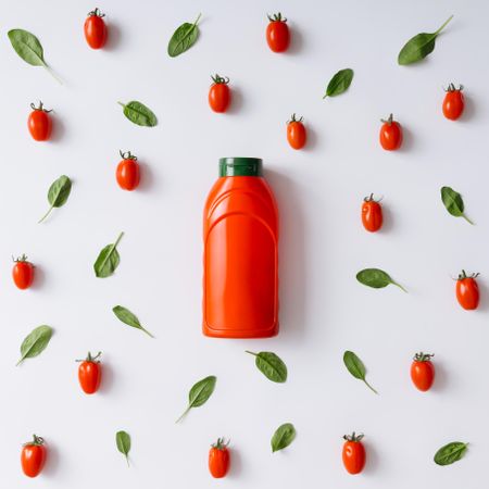 Ketchup bottle on tomato and basil pattern on light background