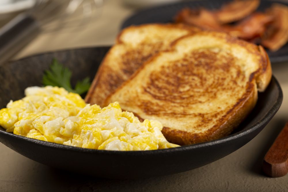 Breakfast. Scrambled egg with toast and bacon.