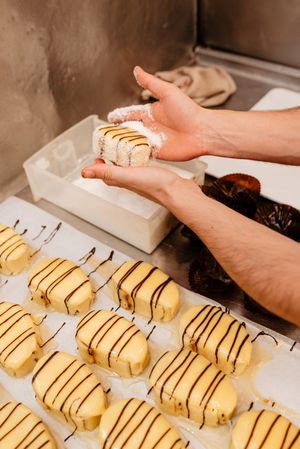Crop confectioner covering pastry with coconut flakes