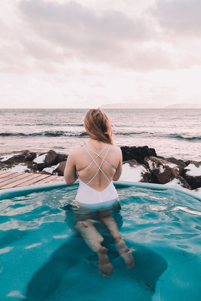 Woman sitting in pool near stones