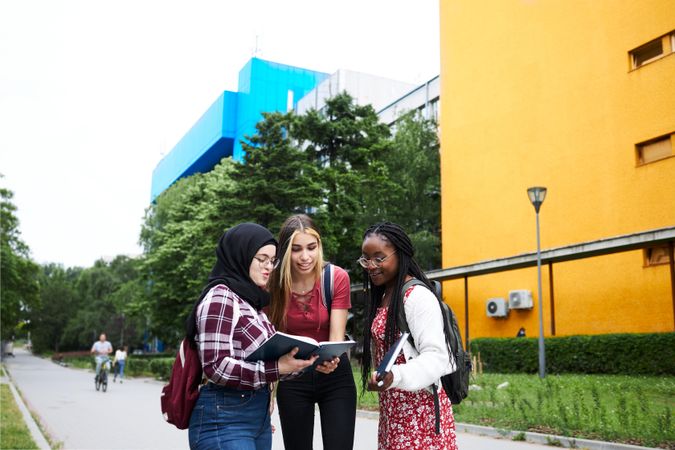 Three friends checking a textbook before class