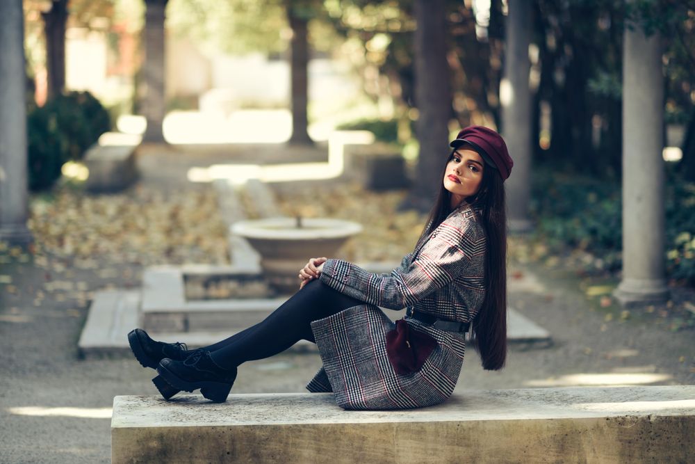 Female in warm winter clothes relaxing on park stoop looking at camera