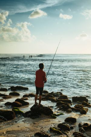 Back of man fishing at Bali coast