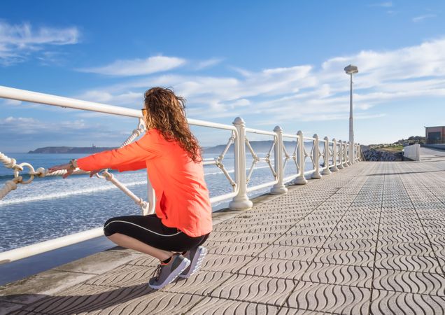Athletic woman crouched down on the beach promenade on a summer morning