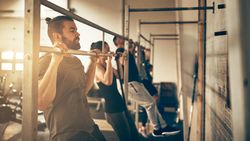 Row of people doing chin ups in gym