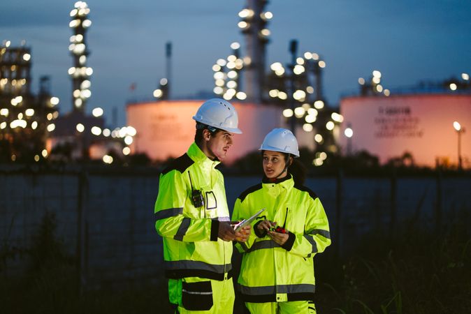 Two industrial workers observing and discussing at refinery factory