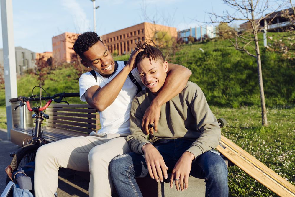 Young Black men playing on street bench