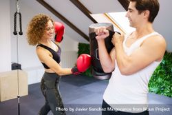 Woman punching punching bag with male trainer 0V6EwN
