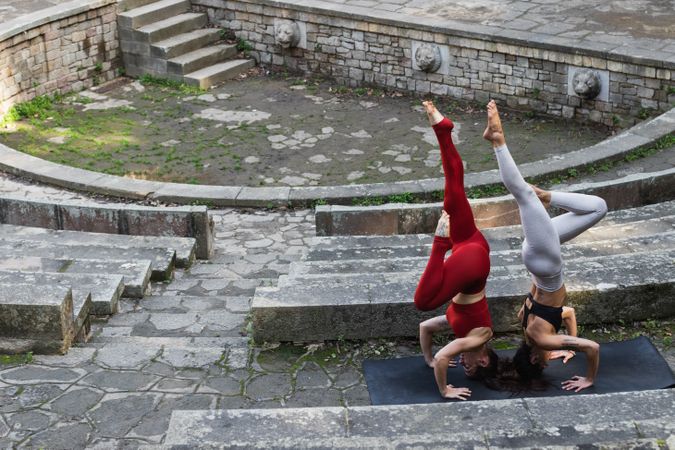 Slender women practicing yoga in headstand on mat