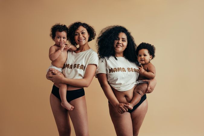 Two women wearing mama bear t-shirts holding their babies