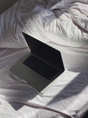 Personal computer in morning light on bedsheets