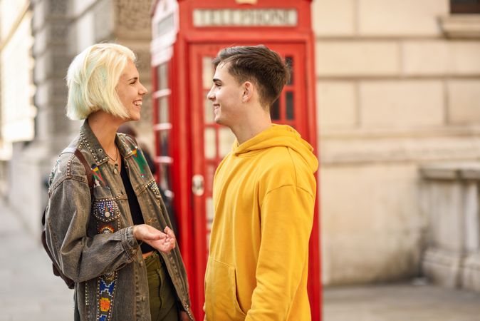 Man and woman looking at each other in front of a phone booth