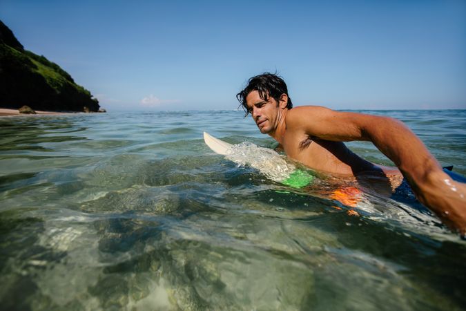Young man drifting on surfboard in the ocean