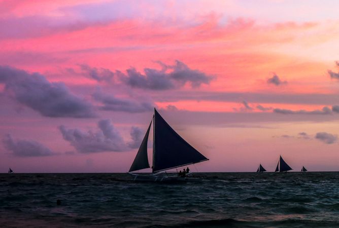 Silhouette of boats sailing in sea during sunset