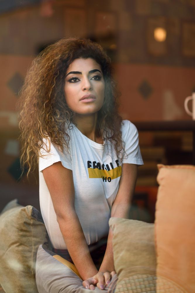 Arab woman looking wistfully out of cafe window