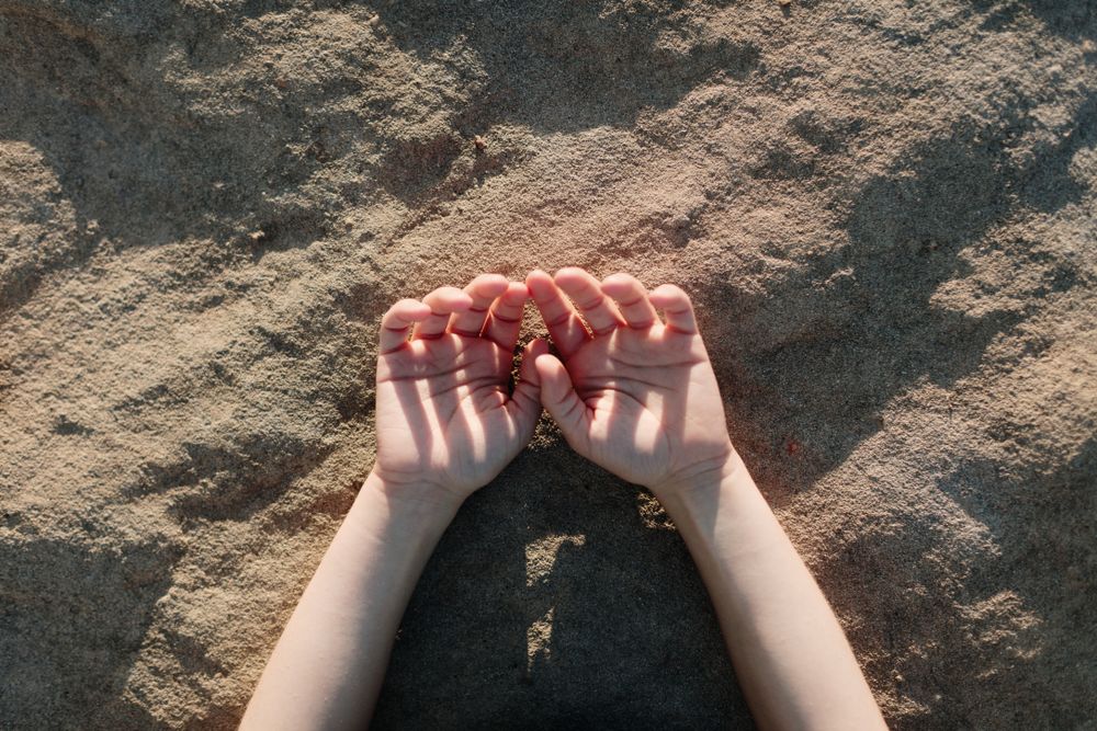 Close up of hands resting on the ground